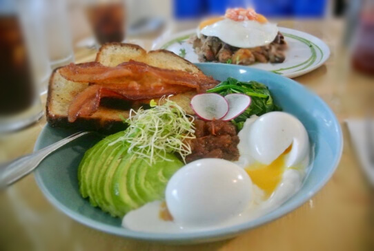 Two over easy eggs with avacado, beans, bacon and toast.