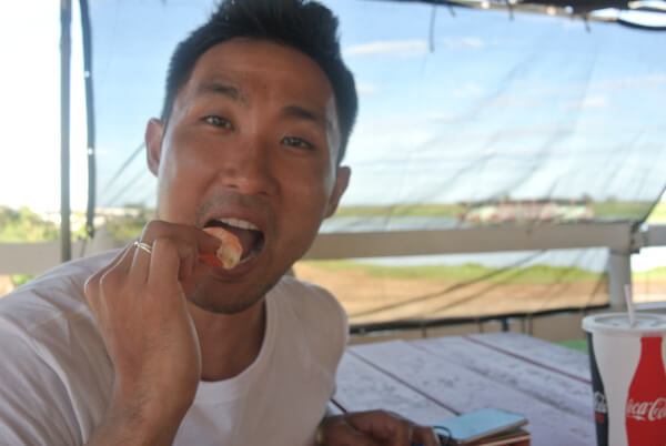 Man eating a shrimp outside in Oahu.