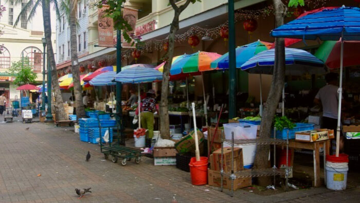 Chinatown market in Honolulu. Open umbrellas over various produce.