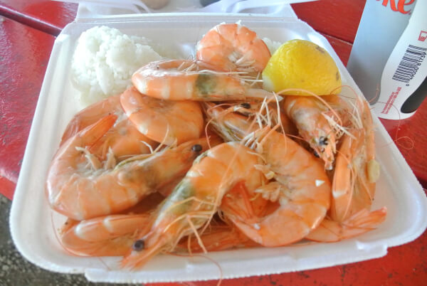 a plate of large prawns, rice and a lemon wedge.